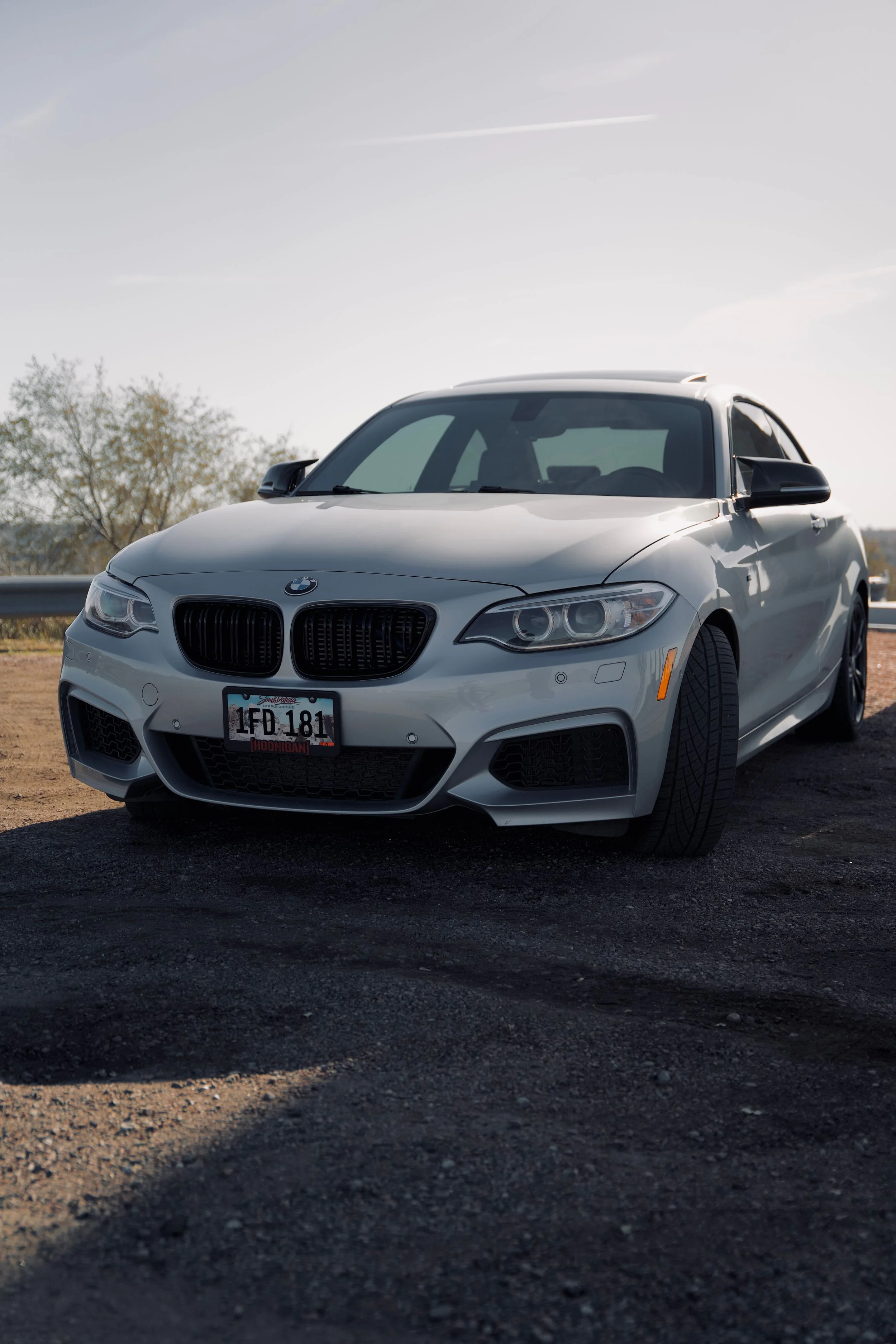 A silver BMW sedan parked on asphalt beneath an overcast sky.