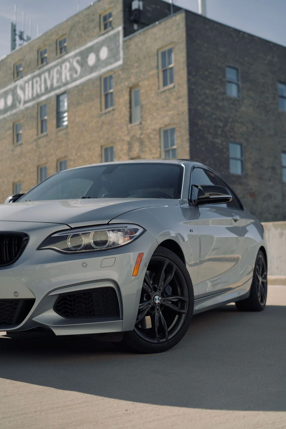 A silver BMW sedan parked in front of a downtown building.