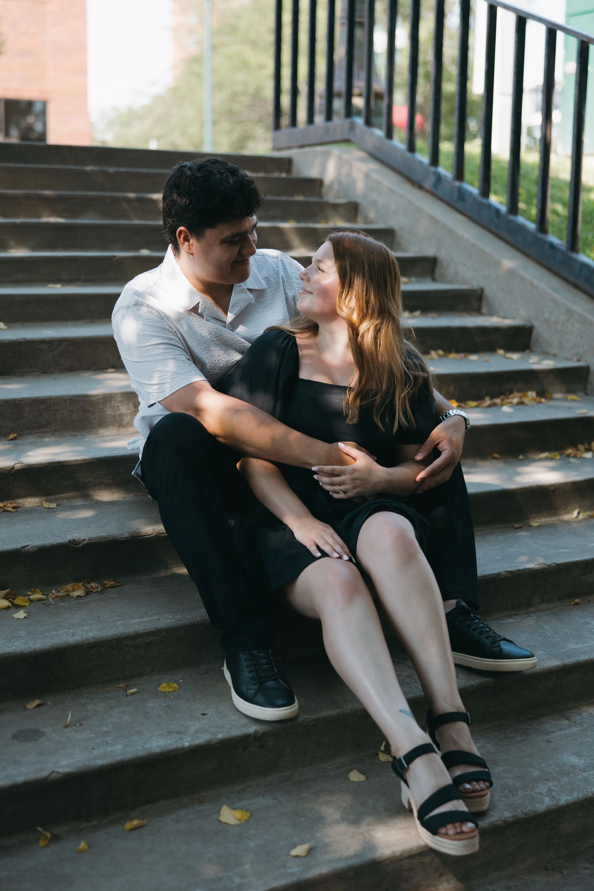 A couple seated together on outdoor concrete steps.